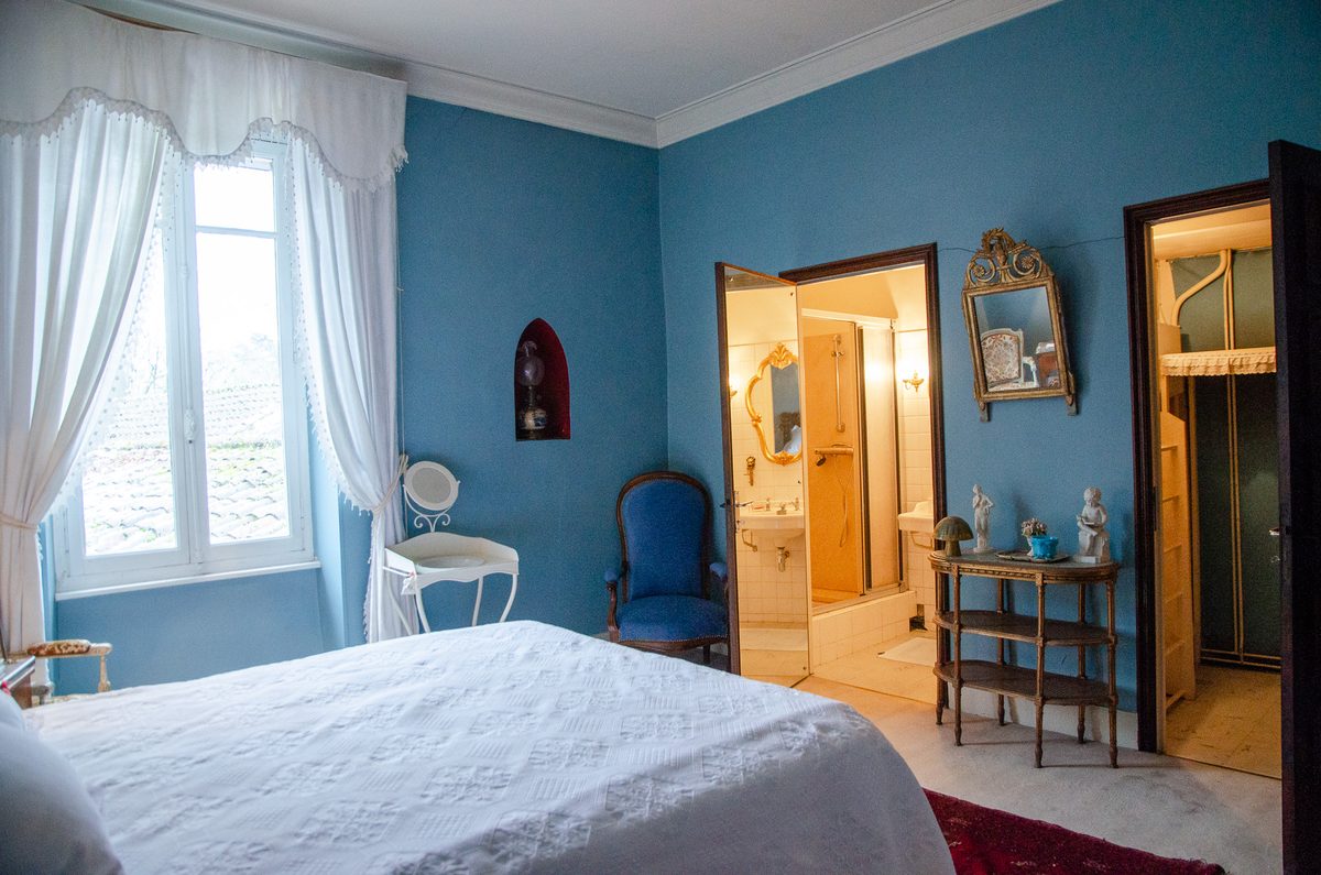 Chambre aux murs bleus avec sa salle d'eau attenante, ouverte sur le parc