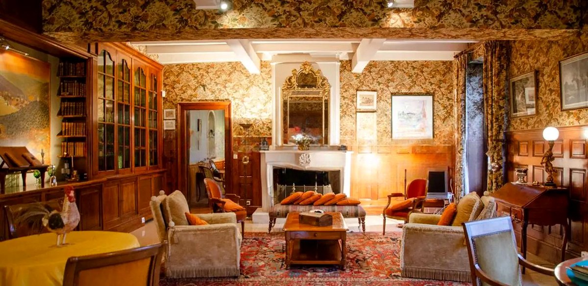 Le grand salon : boiseries, bibliothèque vitrée, cheminée de marbre et tapisserie à motifs