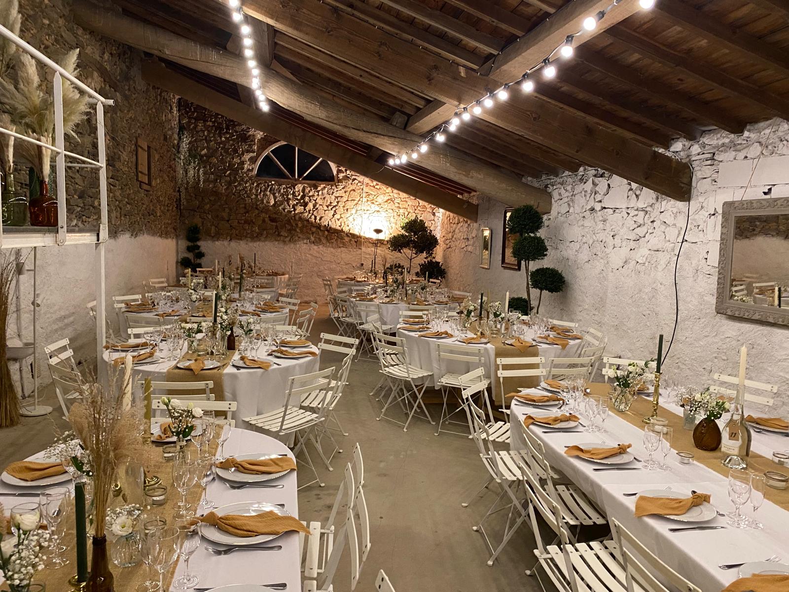 Salle de réception pour mariage à Castres - tables rondes dressées avec guirlandes lumineuses et murs en pierre
