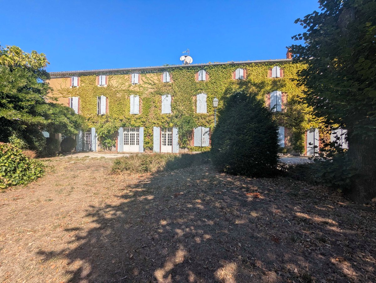 The park and the house with its shutters open, seen from the far end of the grounds
